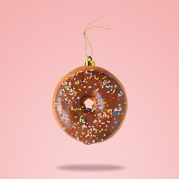 Christmas bauble decoration made of chocolate doughnut on pink background. Minimal concept.