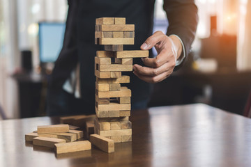 Businessman picking wooden block fail danger tower hands playing challenge game building...
