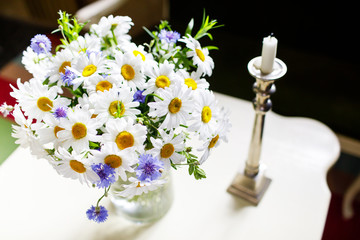 bouquet of chamomiles in a glass vase on a wooden table.