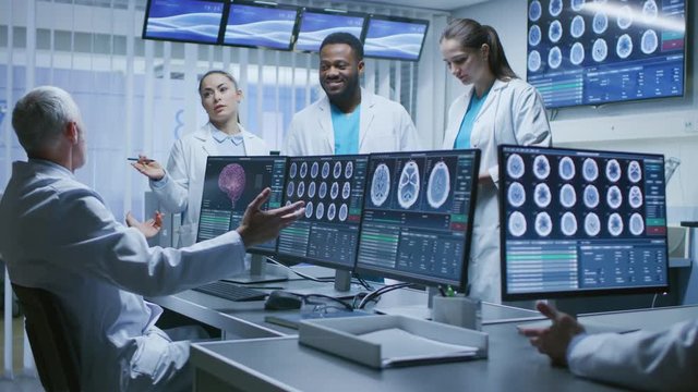 Team of Professional Medical Scientists Work in the Brain Research Laboratory. Neurologists / Neuroscientists Having Heated Discussion Surrounded by Monitors Showing CT, MRI Scans.

