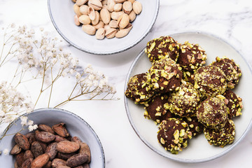 Homemade healthy vegan chocolate avocado truffles with pistachio in the bowl and ingredients on grey marble table. Organic energy vegetarian sweet balls