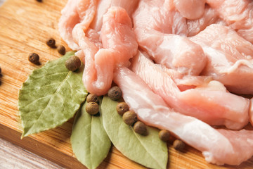 Pieces of fresh chicken fillet, bay leaf and black pepper on a wooden background