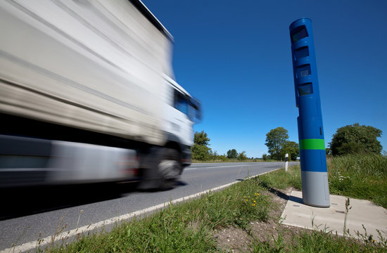 ein LKW passiert in schneller Fahrt eine blaue Maut-S&auml;ule an einer Bundesstra&szlig;e in Deutschland