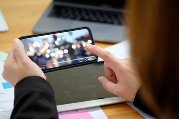 Close up of women's hands holding mobile phone while play video from network in office.