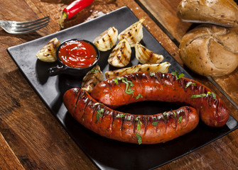 Grilled sausages in a plate on wooden background