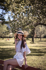 Pretty young woman in a summer garden, casual romantic style with hat