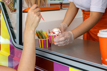 Seller's hands from the window stretches a wafer of soft cream ice cream. Street Trading