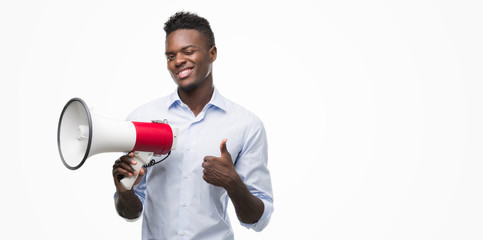 Young african american man holding megaphone happy with big smile doing ok sign, thumb up with fingers, excellent sign