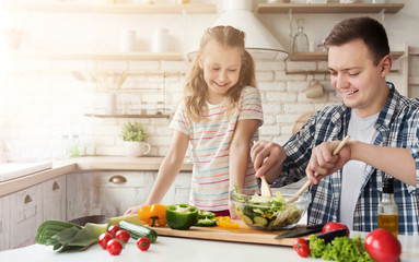 Dad and little daughter cooking in kitchen at home