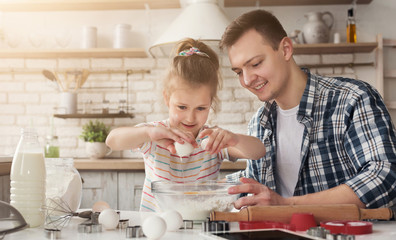 Dad and daughter cooking surprise cake for mom