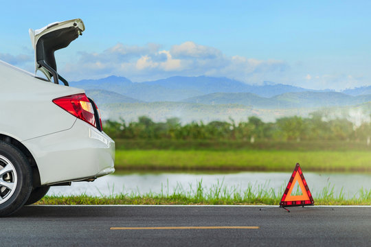 Problems car and a red triangle warning sign on the road
