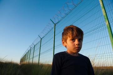sad poor little child with mud on face near barbed wire fence mexican usa border