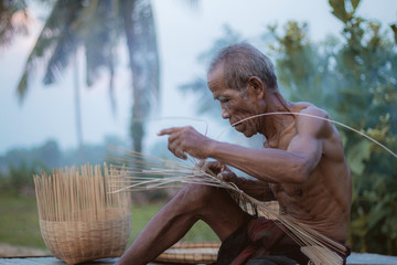 Old man are weaving basket of Thailand.