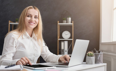 Smiling accountant sitting by laptop and looking at camera