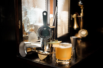 Yellow cocktail and essential barman equipment on the sill