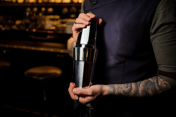 Professional bartender holding the steel cocktail shaker