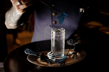 Bartender decorate a cocktail glass with a transparent blue caramel sheet