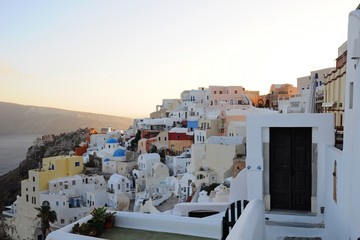 Fototapeta premium Famous stunning view of white architectures and colorful houses above the volcanic caldera in the village of Oia in Santorini island, Greece