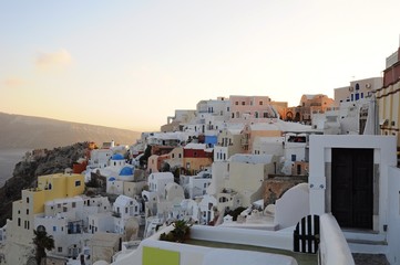Fototapeta na wymiar Famous stunning view of white architectures and colorful houses above the volcanic caldera in the village of Oia in Santorini island, Greece
