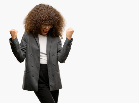 African american business woman wearing glasses very happy and excited doing winner gesture with arms raised, smiling and screaming for success. Celebration concept.