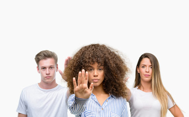 Group of young people over white background with open hand doing stop sign with serious and confident expression, defense gesture