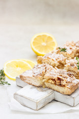 Lemon crumble cake slices or bars on white wooden cutting board, selective focus. Jam bars snack food