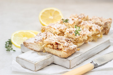 Lemon crumble cake slices or bars on white wooden cutting board, selective focus. Jam bars snack food