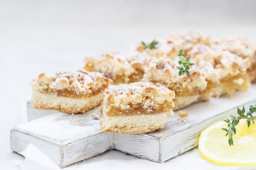Lemon crumble cake slices or bars on white wooden cutting board, selective focus. Jam bars snack food