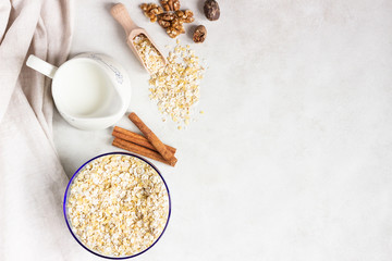 Multigrain cereal flakes in a blue glass bowl, jug of milk, spices (nutmeg and cinnamon) and walnuts. Ingredient for preparing healthy breakfast. Concept of healthy food. Copy space for text.