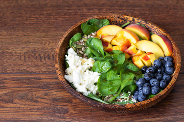 Summer spinach and fruit salad with seeds, mozzarella and balsamic vinegar in a bowl. Summer food concept