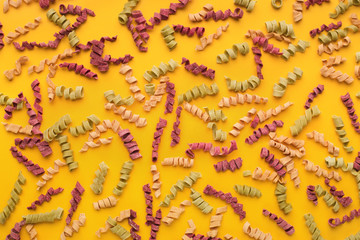 Dried spiral pasta on yellow background