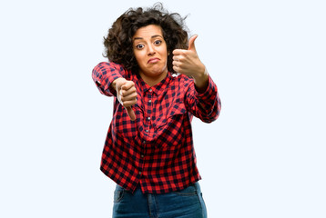 Fototapeta premium Beautiful arab woman confused with thumbs up and down, trying to take a decision expressing doubt and frustration
