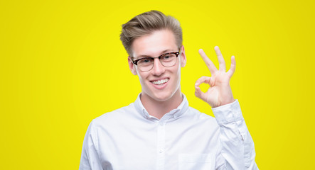 Young handsome blond man smiling positive doing ok sign with hand and fingers. Successful expression.