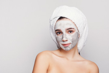 Beautiful girl with applied clay mask at grey background