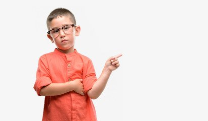 Dark haired little child wearing glasses very happy pointing with hand and finger to the side