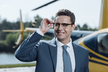 Successful CEO. The close up of a handsome young CEO adjusting his glasses and posing for the camera at a helipad