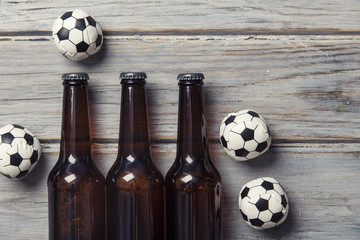 Beer bottle with soccer football balls on a wooden background