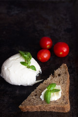 Fresh basil, mozzarella cheese and cherry tomatoes on dark background. Italian food or ingredients background. Caprese. Copy space, top view.