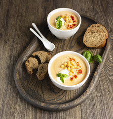 Cream soup with cauliflower, chickpea and sour cream on a dark wood background, top view. Healthy food concept 