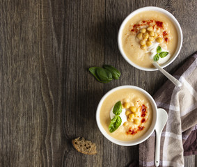 Cream soup with cauliflower, chickpea and sour cream on a dark wood background, top view. Healthy food concept 