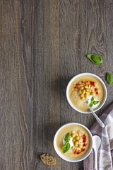 Cream soup with cauliflower, chickpea and sour cream on a dark wood background, top view. Healthy food concept 