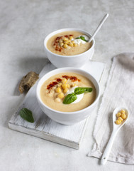 Cream soup with cauliflower, chickpea and sour cream on a light grey background, top view. Healthy food concept 