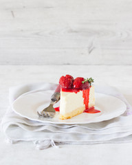 Piece of delicate cheesecake with strawberries sauce on a white plate. 