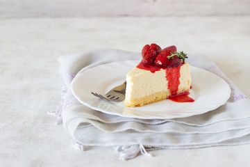 Piece of delicate cheesecake with strawberries sauce on a white plate. 