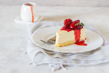 Piece of delicate cheesecake with strawberries sauce on a white plate. 
