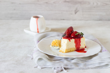 Piece of delicate cheesecake with strawberries sauce on a white plate. 