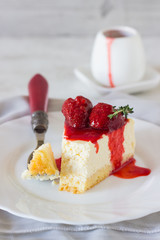 Piece of delicate cheesecake with strawberries sauce on a white plate. 