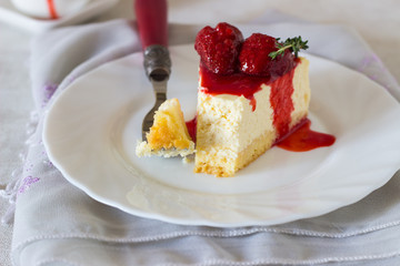 Piece of delicate cheesecake with strawberries sauce on a white plate. 