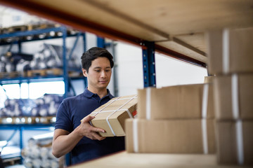 Male picking up box from shelf in distribution warehouse