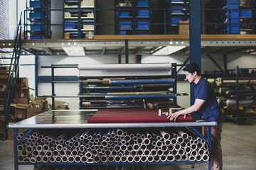 Male cutting fabric in a manufacturing warehouse